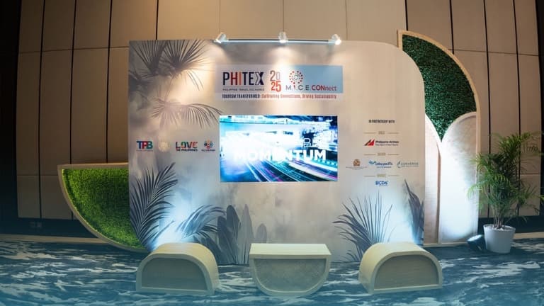PHITEX 2025 booth with a screen, seating and plants