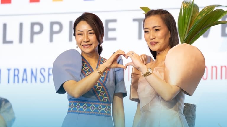 Two speakers making a heart sign on stage at PHITEX 2025